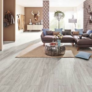 Ein braunes Sofa in einem Raum mit Teppich und Laminatboden