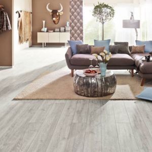 Ein braunes Sofa in einem Raum mit Teppich und Laminatboden