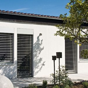 Ein weißes Massivhaus mit Terasse bei sonnigem Wetter