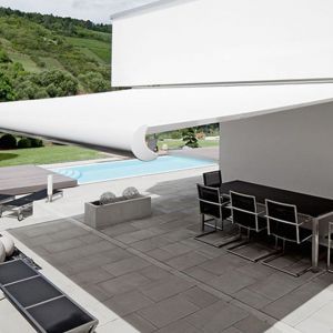 Ein weißes Massivhaus mit eine Terrasse und einer weißen Markise